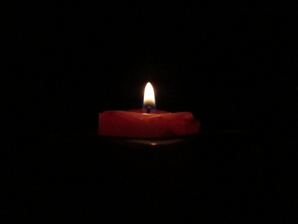 red lighted candle on dark room