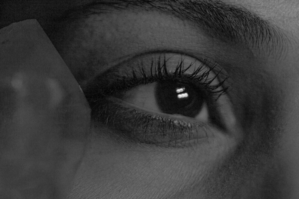 Black and white closeup part of face of anonymous dreamy enigmatic female with brown eyes and long eyelashes looking away thoughtfully