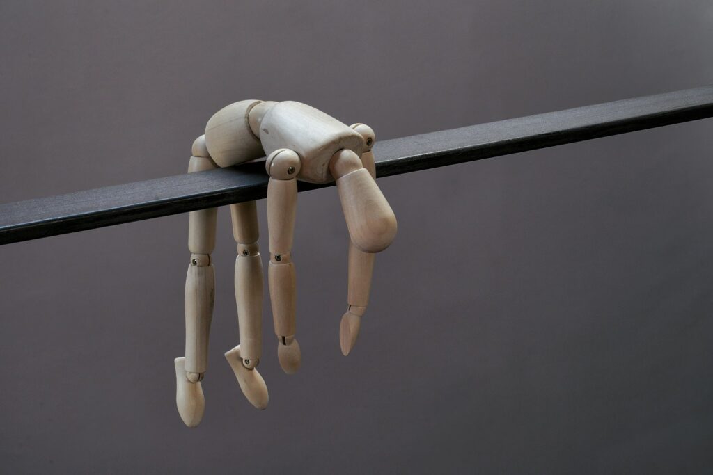 Mannequin doll hangs limply from a dark beam.