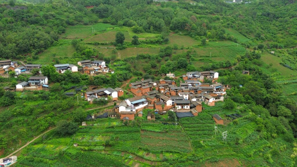 an aerial view of a village surrounded by lush green hills