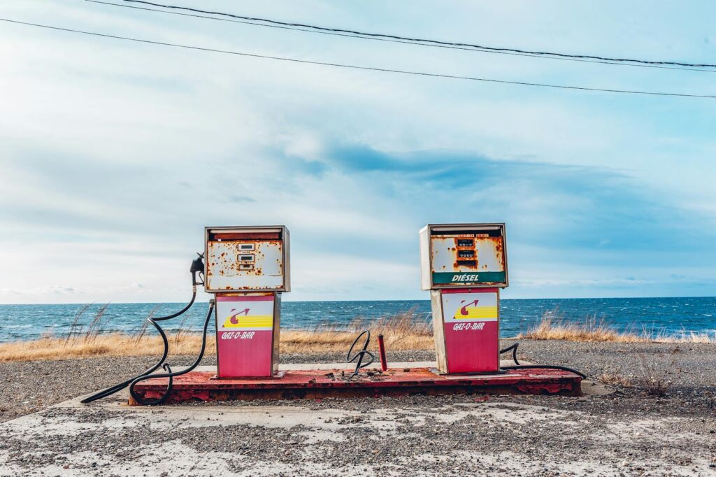 Vintage gas pumps on a deserted seashore with a clear sky and ocean view.