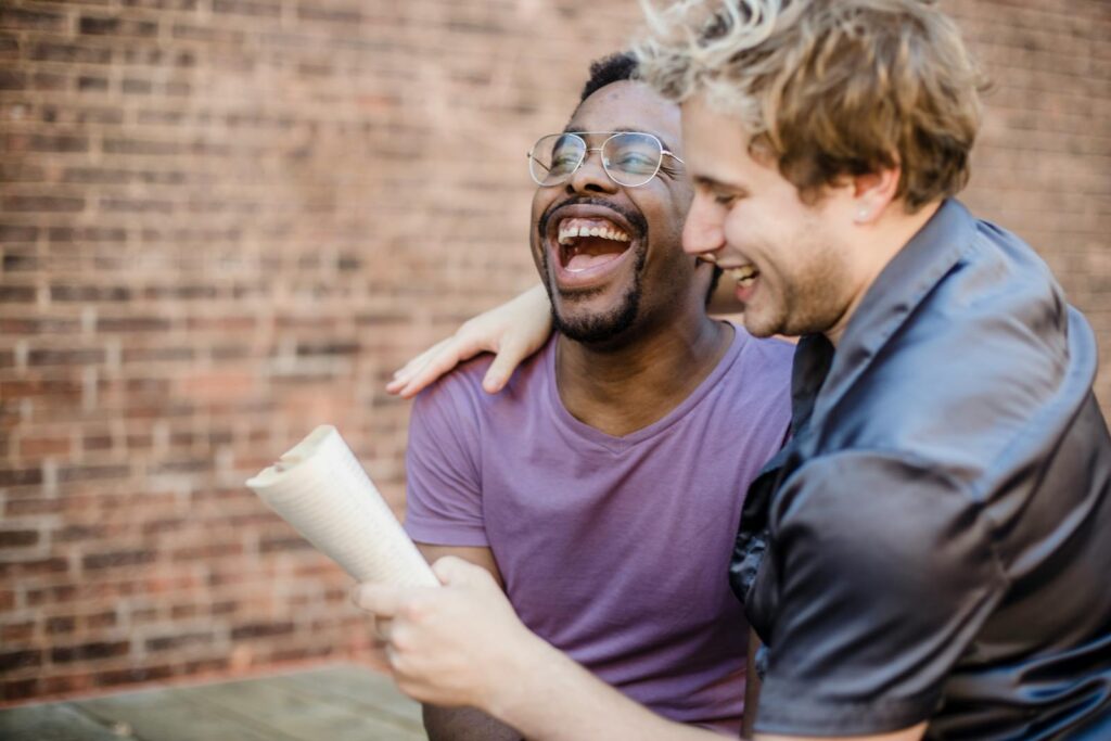 Two happy men in a loving, joyful moment, sharing laughter on a sunny day.