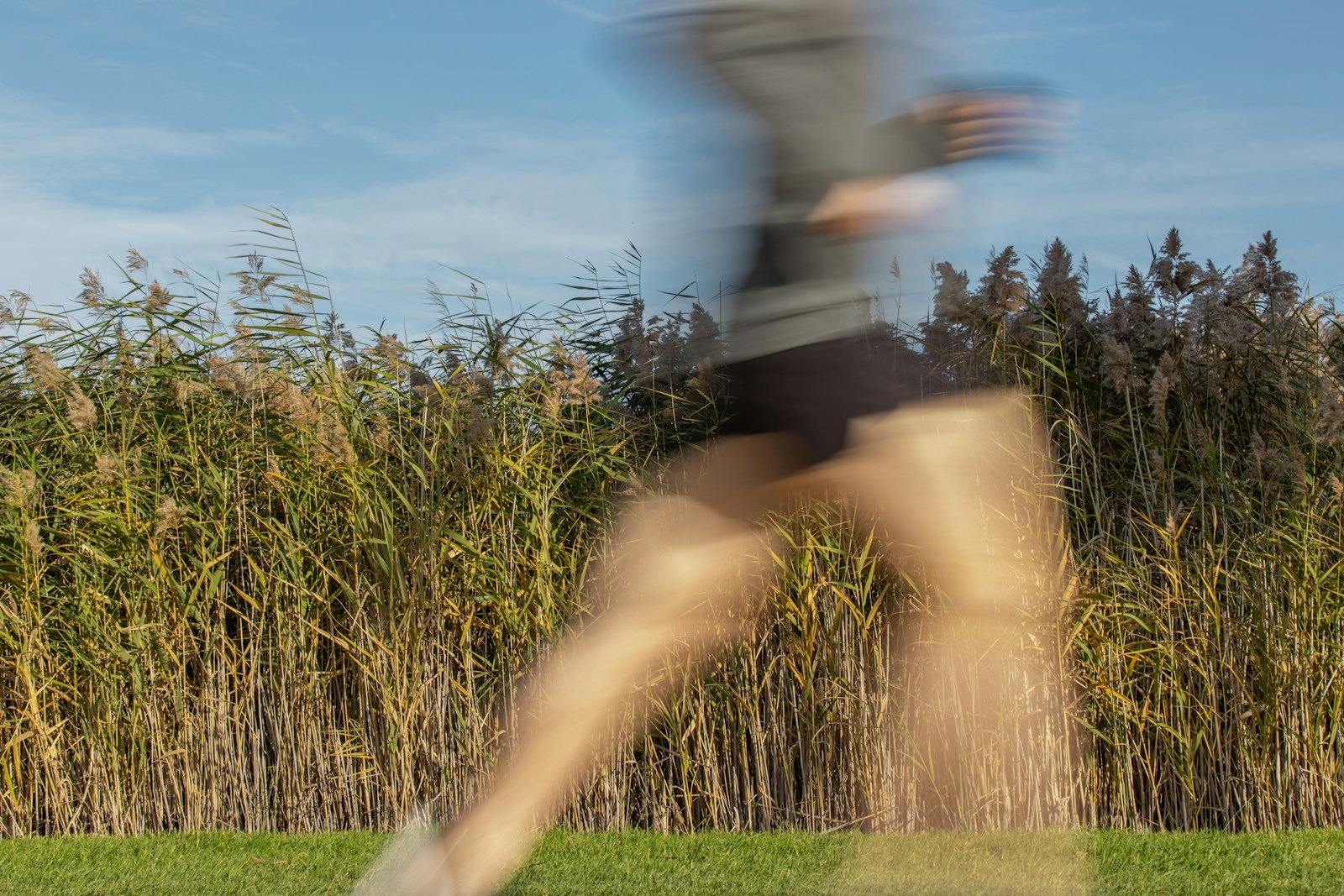 man in black shorts and black shirt jumping on green grass field during daytime