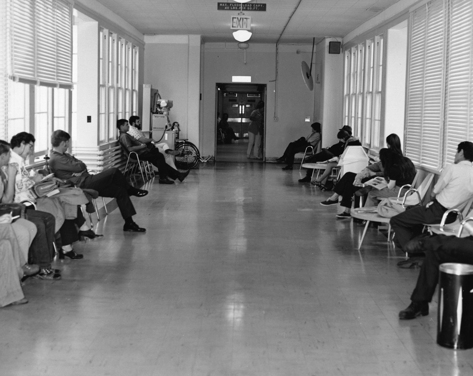 People waiting in a hallway with chairs and chairs