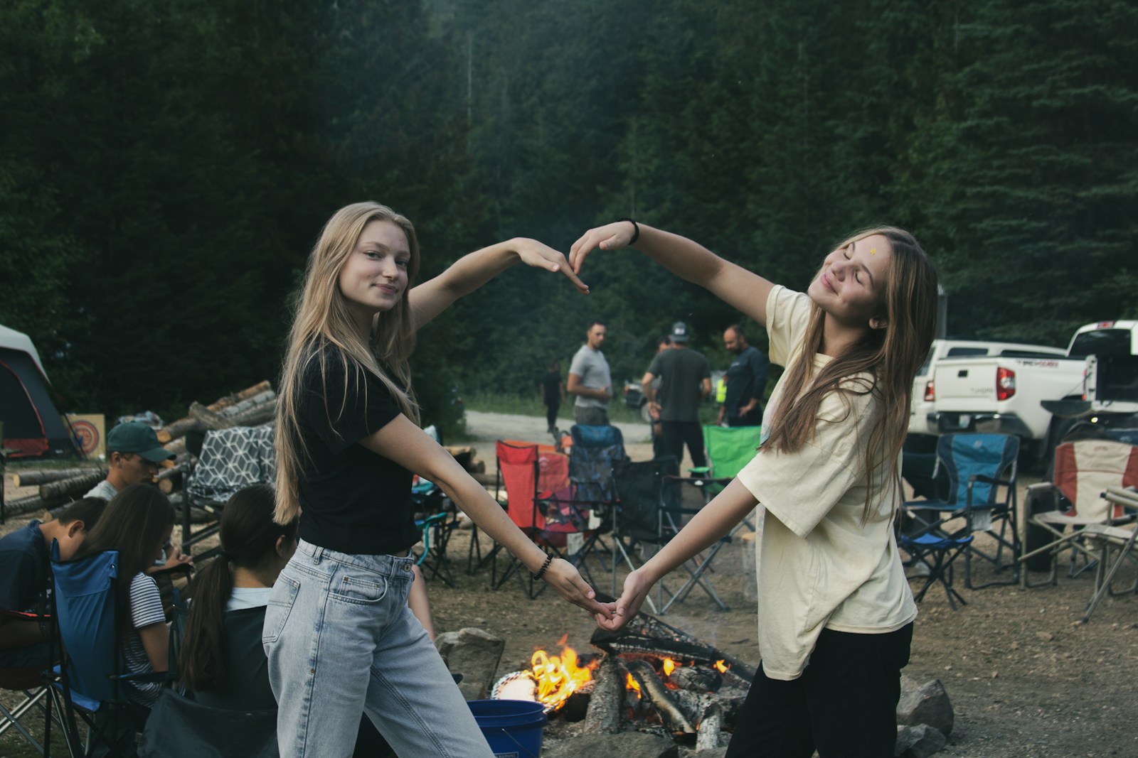 a couple of girls standing next to a fire