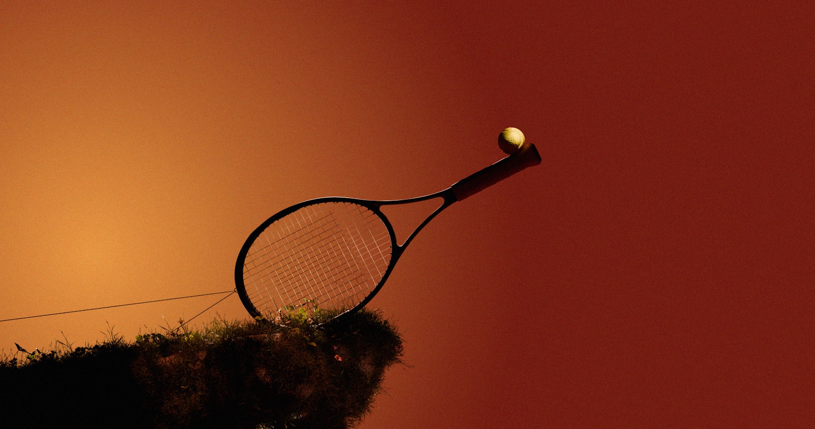 Tennis racket hitting a ball against an orange sky